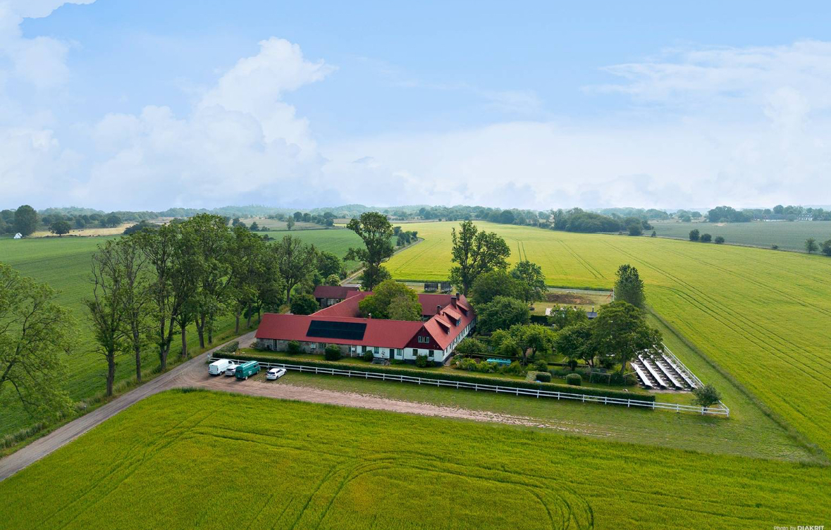 Aerial view of Alexander Lervik's studio — a long red-roofed farm building surrounded by fields in Österlen